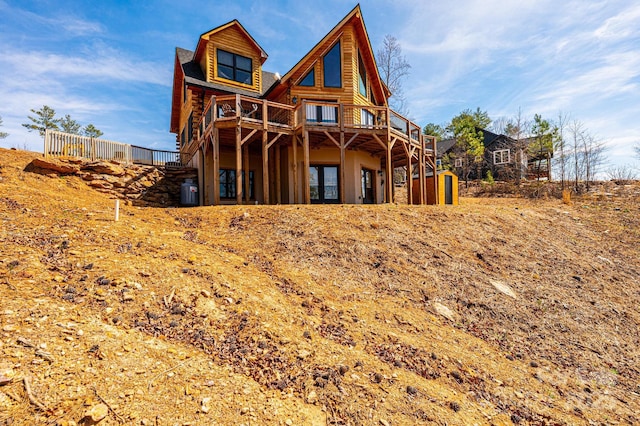 rear view of house with log exterior, a wooden deck, and stairs
