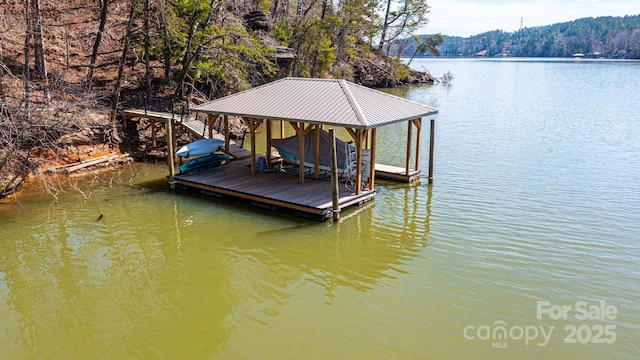 view of dock featuring a view of trees, boat lift, and a water view