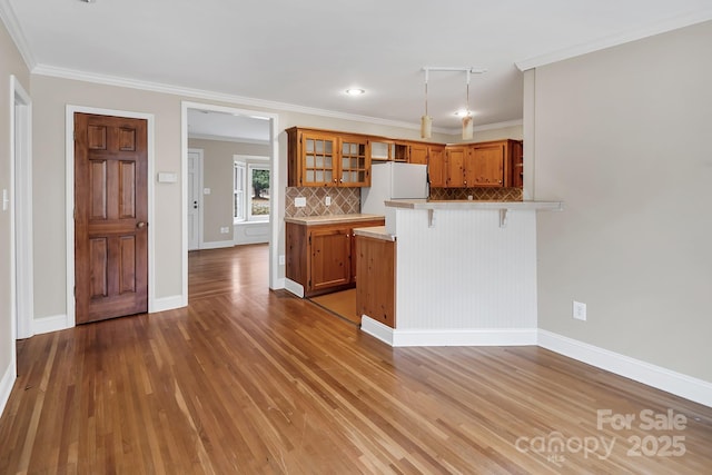403 Hillcrest Dr, Huntersville, NC 28078 - kitchen with tasteful backsplash, a breakfast bar area, freestanding refrigerator, a peninsula, and brown cabinetry