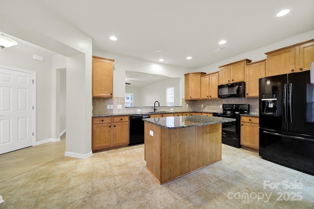 kitchen featuring a kitchen island, dark stone countertops, a sink, black appliances, and backsplash