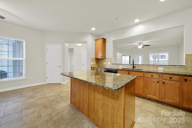 kitchen featuring brown cabinets, ceiling fan, a sink, and a kitchen island