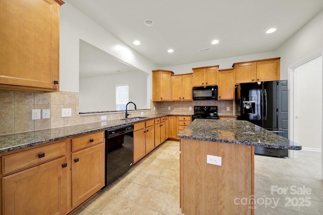 kitchen featuring tasteful backsplash, a center island, dark stone countertops, a sink, and black appliances