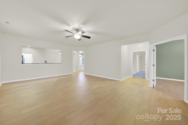 unfurnished living room featuring a ceiling fan, baseboards, and light wood-type flooring