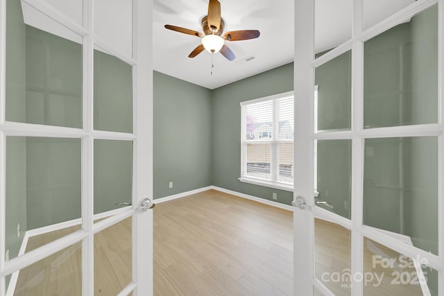 empty room featuring french doors, wood finished floors, baseboards, visible vents, and ceiling fan