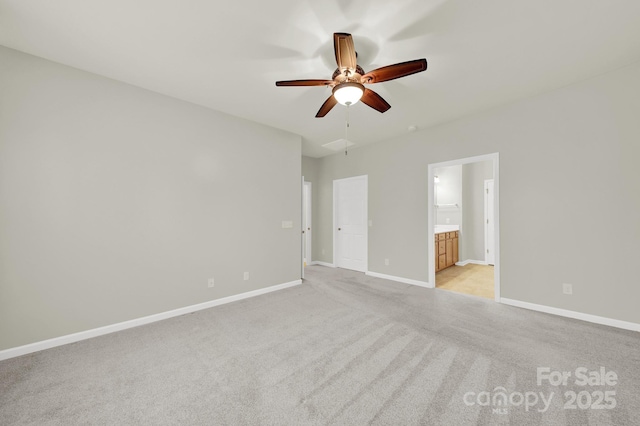 unfurnished bedroom with ensuite bathroom, light colored carpet, ceiling fan, and baseboards