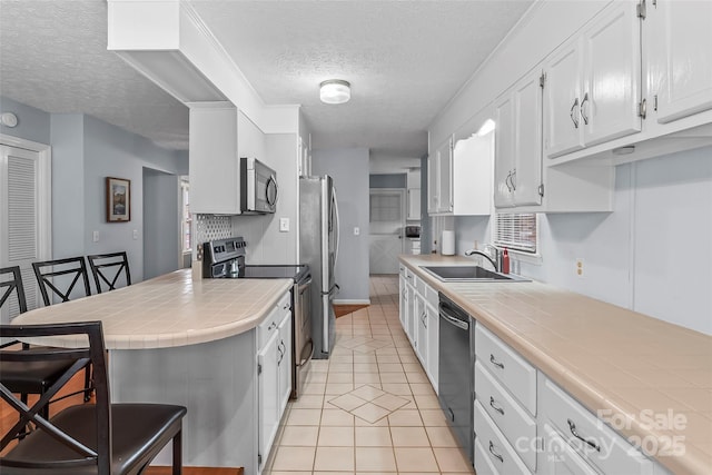 3829 Norman Rd, Morganton, NC 28655 - kitchen featuring a sink, a kitchen bar, stainless steel appliances, tile countertops, and white cabinets