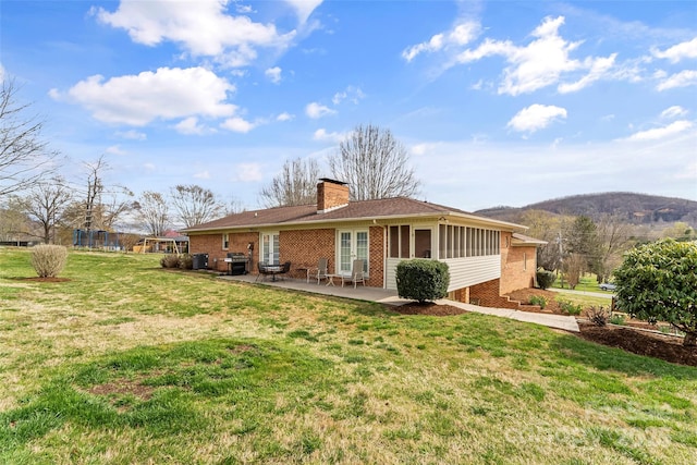 3829 Norman Rd, Morganton, NC 28655 - rear view of property featuring a chimney, brick siding, a yard, and a patio area