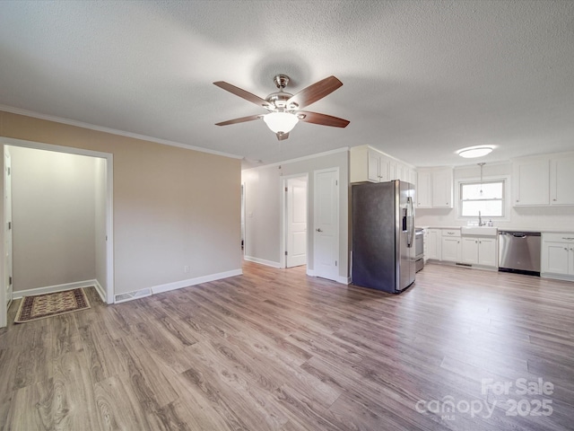 unfurnished living room featuring light wood-style flooring, a sink, ornamental molding, and ceiling fan