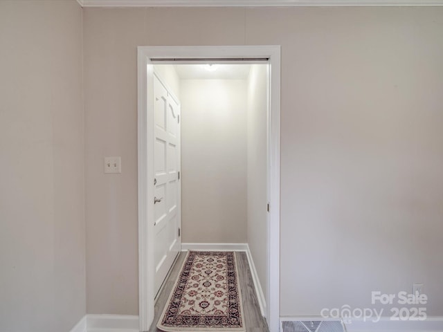 hallway featuring baseboards and visible vents