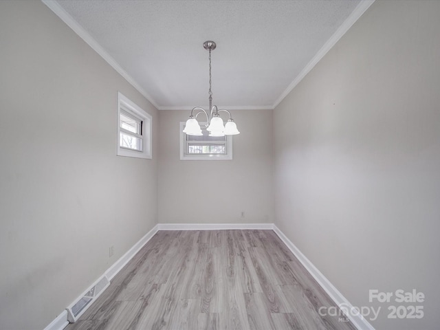 spare room featuring baseboards, visible vents, a chandelier, and light wood finished floors