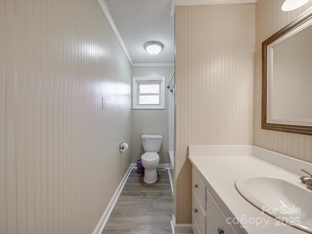 bathroom featuring a textured ceiling, walk in shower, ornamental molding, toilet, and vanity