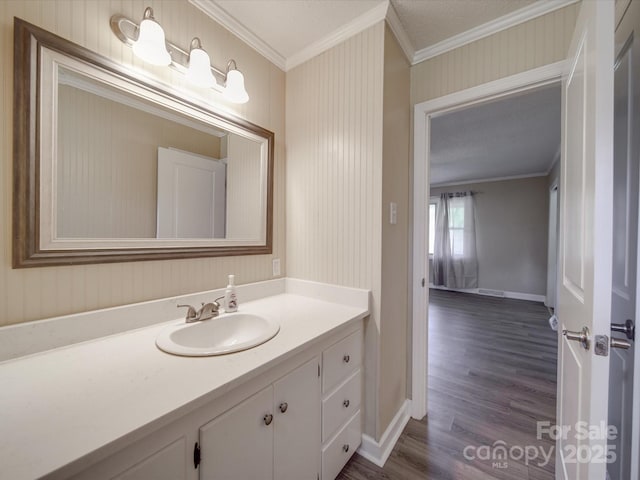 bathroom featuring vanity, baseboards, wood finished floors, and crown molding