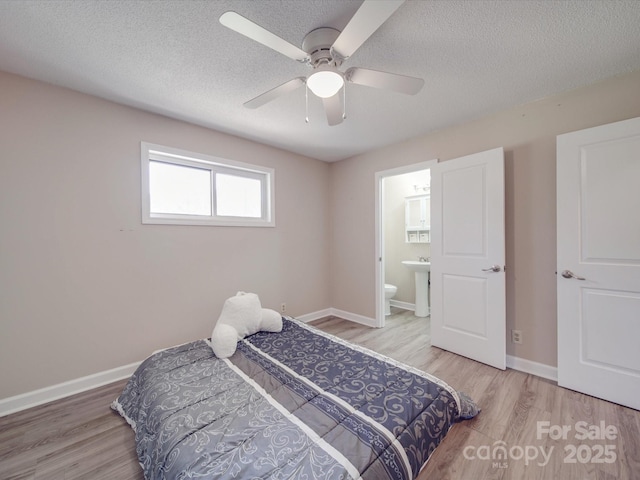 bedroom with baseboards, a textured ceiling, wood finished floors, and ensuite bathroom