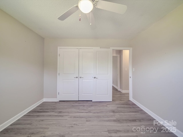 unfurnished bedroom with baseboards, a closet, light wood-style flooring, and a textured ceiling