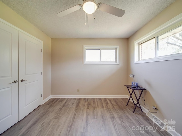 unfurnished room with light wood-style flooring, baseboards, and a textured ceiling