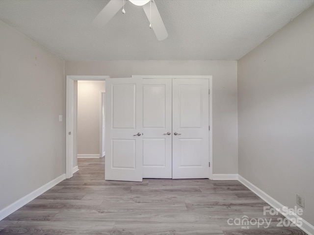 unfurnished bedroom with light wood-style flooring, baseboards, and a textured ceiling