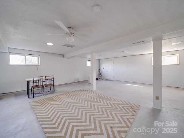 basement featuring a textured ceiling, visible vents, and a ceiling fan