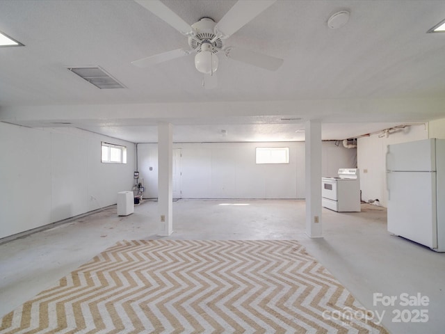 below grade area featuring freestanding refrigerator, a ceiling fan, washer / dryer, and visible vents