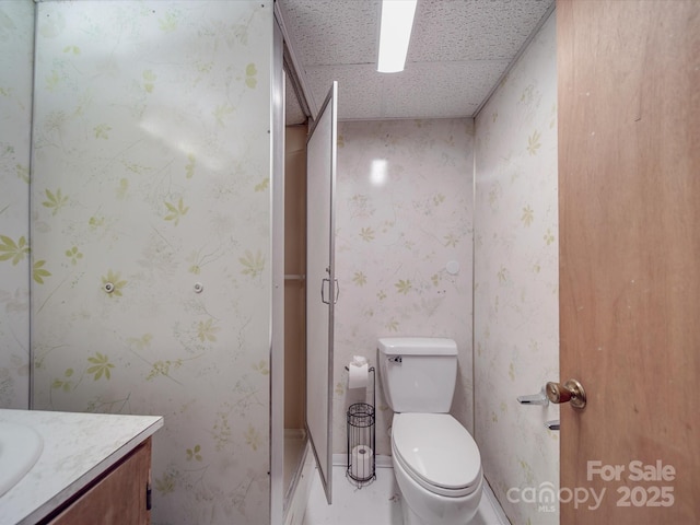bathroom featuring wallpapered walls, toilet, and vanity