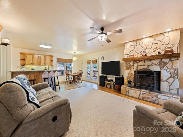 3975 Mountain Creek Rd, Robbinsville, NC 28771 - living room featuring a ceiling fan, a stone fireplace, a textured ceiling, and wood finished floors