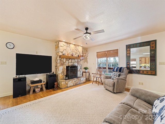 3975 Mountain Creek Rd, Robbinsville, NC 28771 - living room featuring a textured ceiling, a stone fireplace, wood-type flooring, baseboards, and ceiling fan