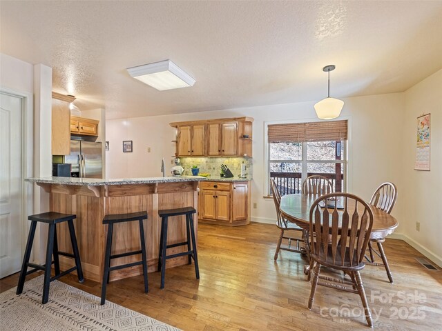 3975 Mountain Creek Rd, Robbinsville, NC 28771 - kitchen featuring tasteful backsplash, a peninsula, stainless steel refrigerator with ice dispenser, visible vents, and light wood-style floors