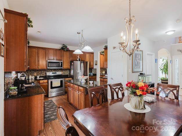 6000 Pine Cone Ln, Monroe, NC 28110 - kitchen with brown cabinets, tasteful backsplash, arched walkways, and appliances with stainless steel finishes