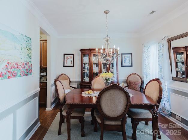 6000 Pine Cone Ln, Monroe, NC 28110 - dining room featuring visible vents, crown molding, a notable chandelier, and dark wood finished floors