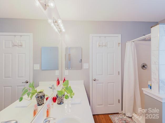 6000 Pine Cone Ln, Monroe, NC 28110 - full bathroom with double vanity, wood finished floors, and a shower with shower curtain
