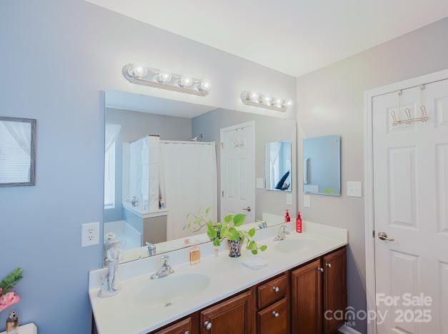 6000 Pine Cone Ln, Monroe, NC 28110 - bathroom featuring double vanity, a shower with shower curtain, and a sink