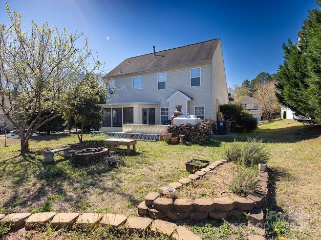 6000 Pine Cone Ln, Monroe, NC 28110 - rear view of house featuring a wooden deck, a sunroom, a fire pit, and a lawn