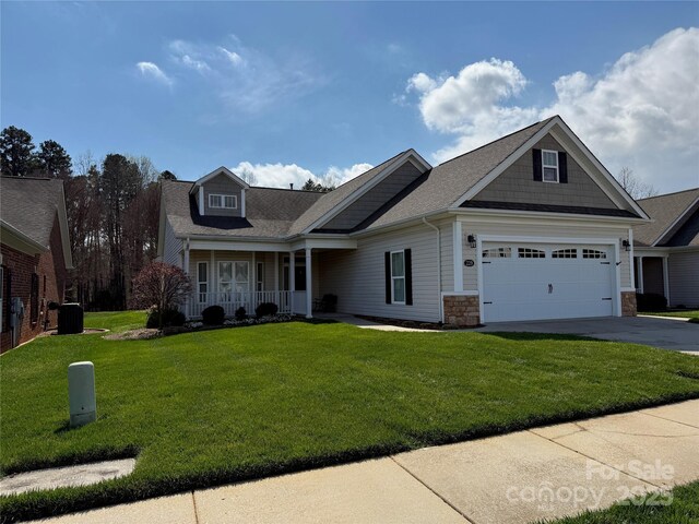 view of front facade featuring stone siding, concrete driveway, a front yard, cooling unit, and a porch