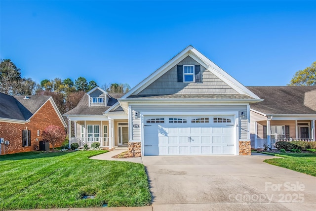 view of front of property with stone siding, an attached garage, concrete driveway, a front yard, and covered porch