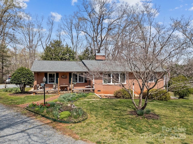 ranch-style home with covered porch, a chimney, brick siding, and a front yard
