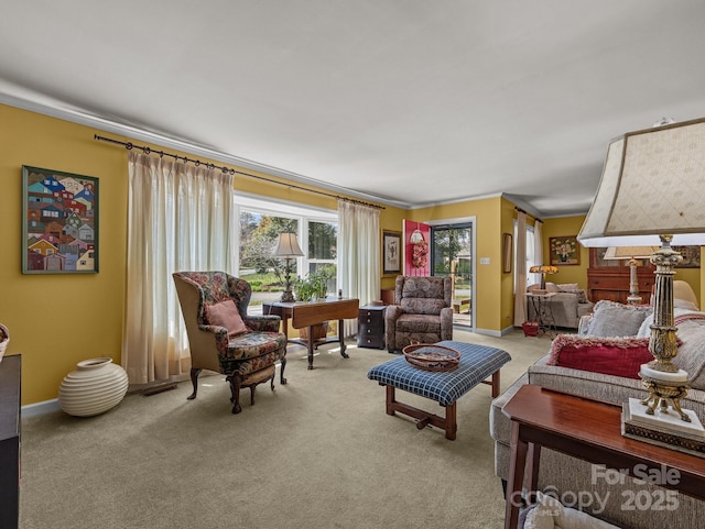 living area with ornamental molding, baseboards, and light colored carpet