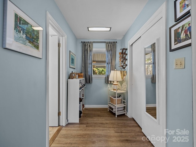 corridor with baseboards and wood finished floors
