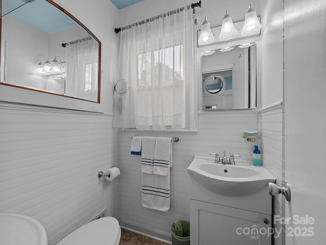 bathroom featuring toilet, vanity, and tile walls