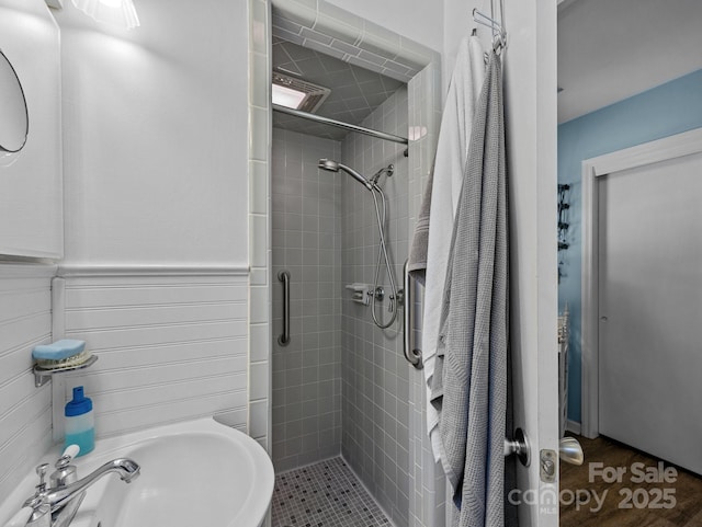 full bath with a sink, a shower stall, and wainscoting