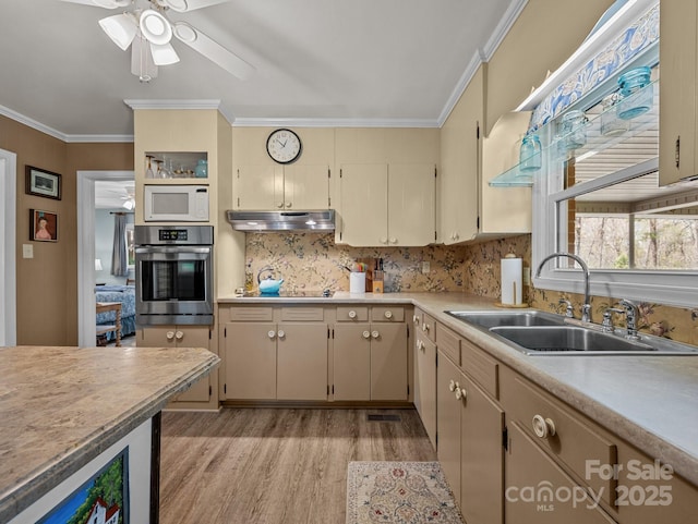 kitchen with light countertops, crown molding, oven, a sink, and white microwave