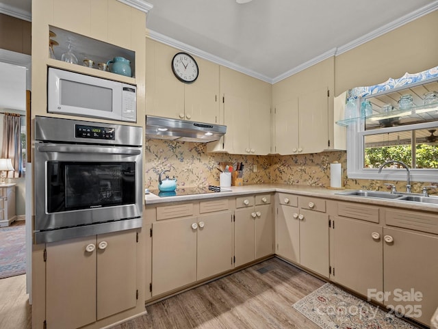 kitchen featuring crown molding, oven, under cabinet range hood, a sink, and white microwave