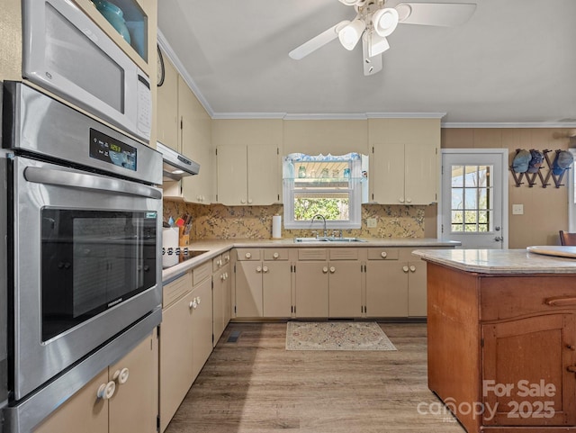 kitchen with a sink, black electric stovetop, white microwave, ornamental molding, and oven