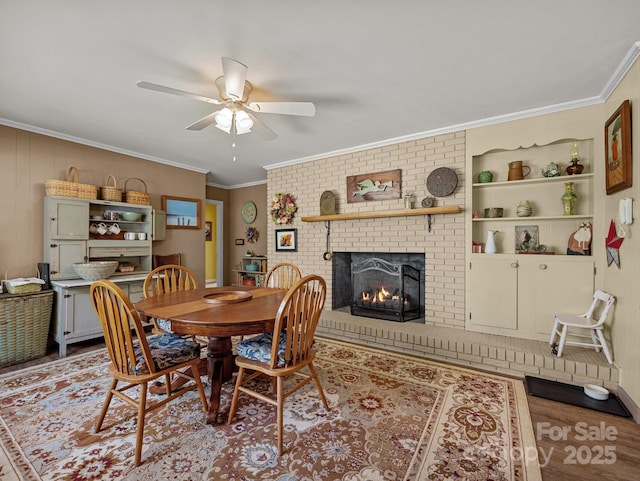dining room featuring a fireplace, wood finished floors, built in features, ceiling fan, and ornamental molding