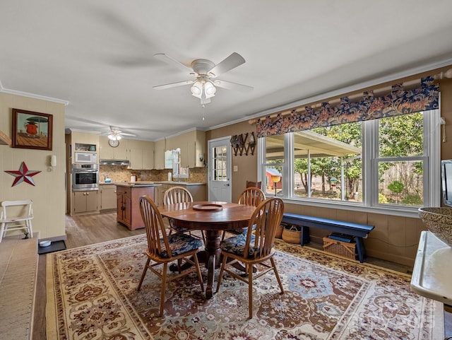 dining area featuring crown molding, light wood-style floors, and a ceiling fan