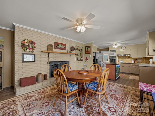 dining area featuring ornamental molding, dark wood-style floors, brick wall, a ceiling fan, and a fireplace