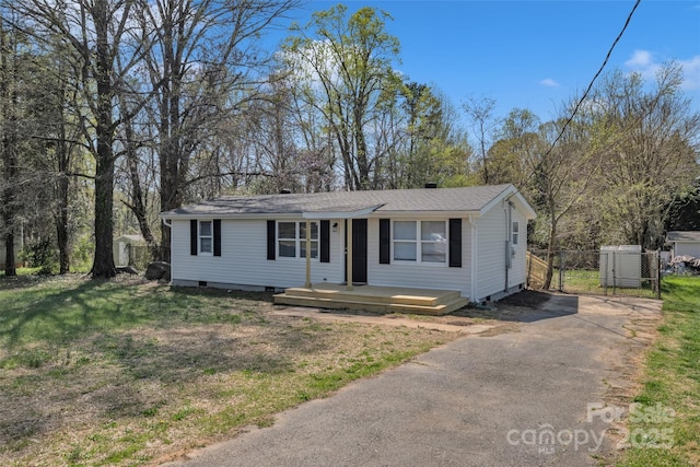 ranch-style house featuring crawl space, driveway, fence, and a front lawn