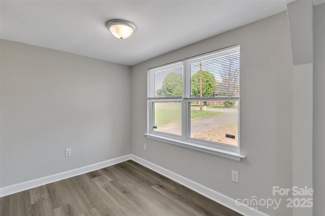 empty room featuring baseboards and dark wood-type flooring