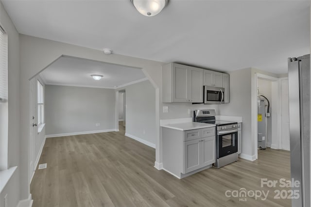 kitchen with light wood-type flooring, light countertops, baseboards, and appliances with stainless steel finishes