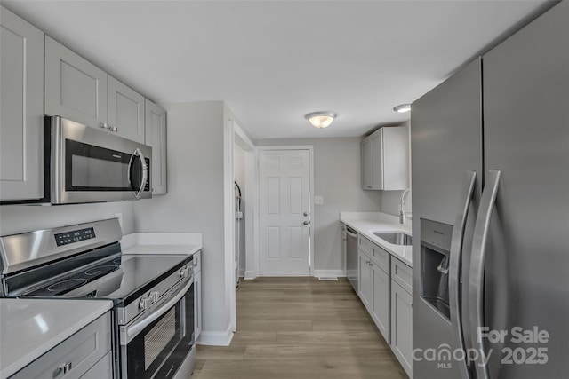 kitchen featuring light countertops, baseboards, appliances with stainless steel finishes, and a sink