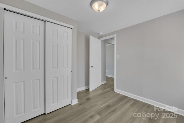 unfurnished bedroom with baseboards, wood finished floors, and a closet