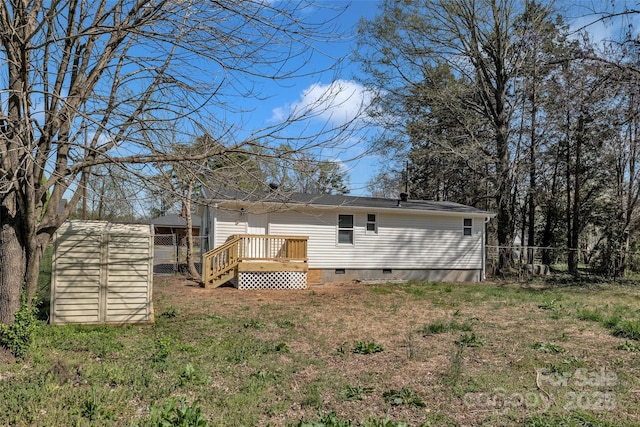 back of house with fence, a storage shed, a wooden deck, crawl space, and an outbuilding